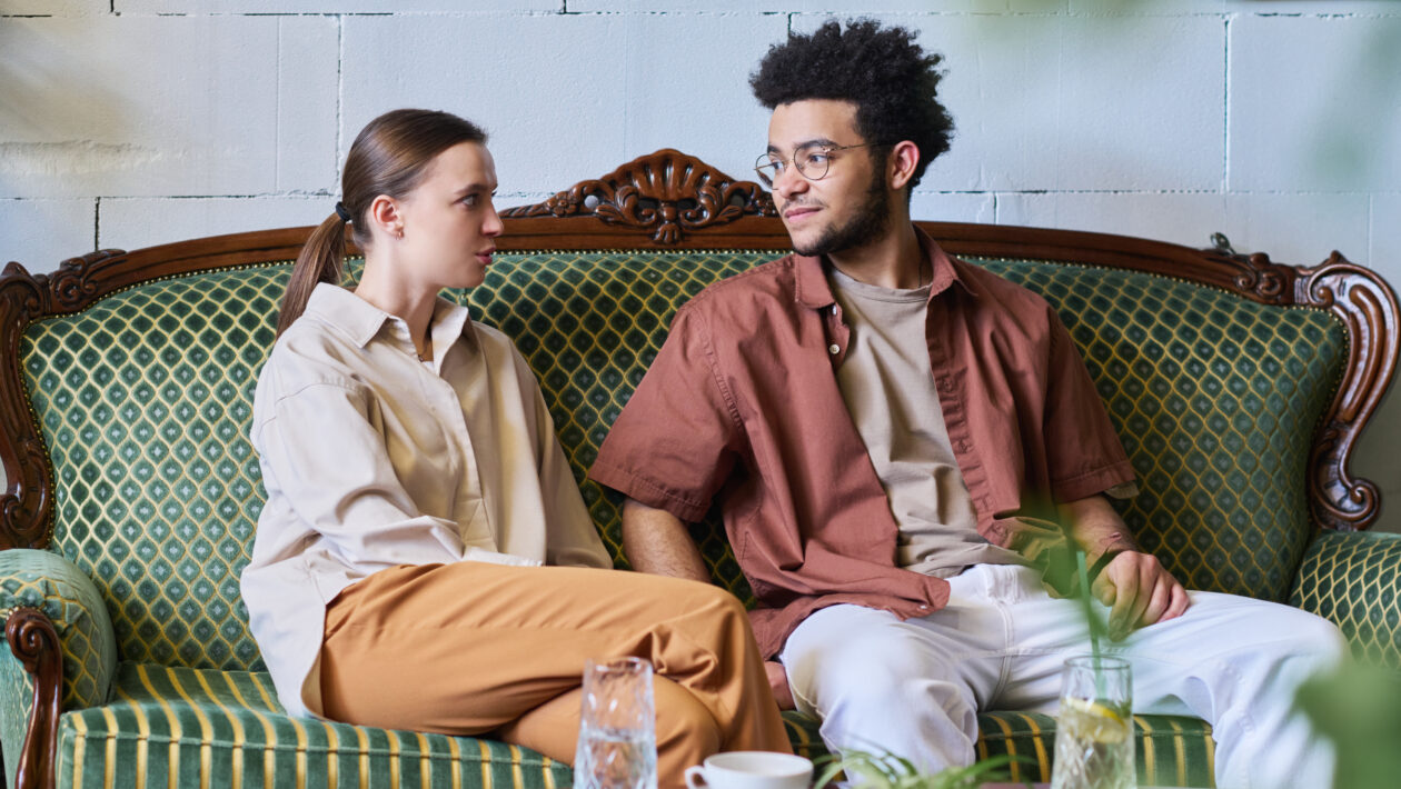 young couple sits on a couch and looks at each other