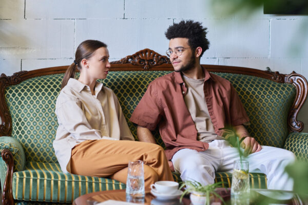 young couple sits on a couch and looks at each other