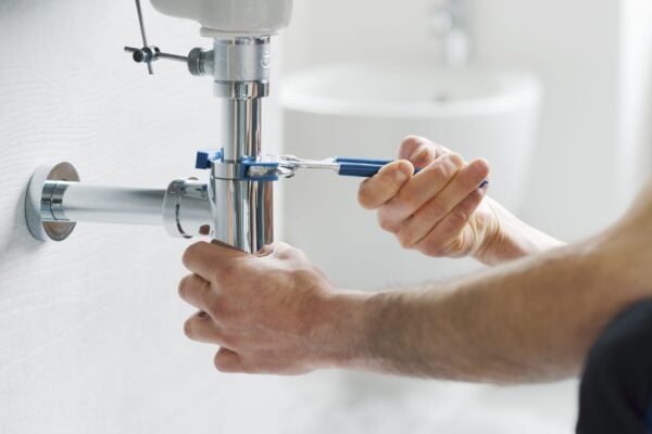 Someone using a wrench on the drain under a sink